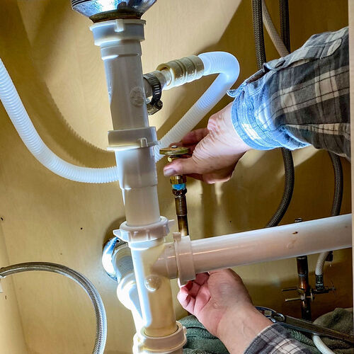 plumber performing repairs on a pipe