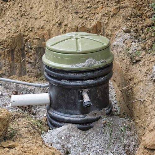 a grinder pump laying in a ditch
